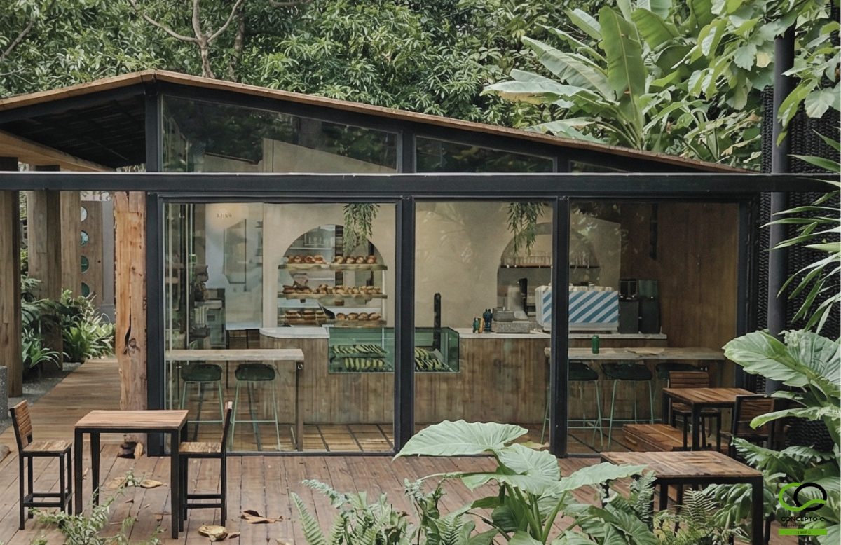 Pabellón de cristal del showroom Concepto Q con la vitrina de pan y las mesas de la terraza